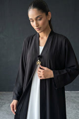 Styled front view of Monochrome Pleated Brooch Abaya showing vertical pintuck pleats
