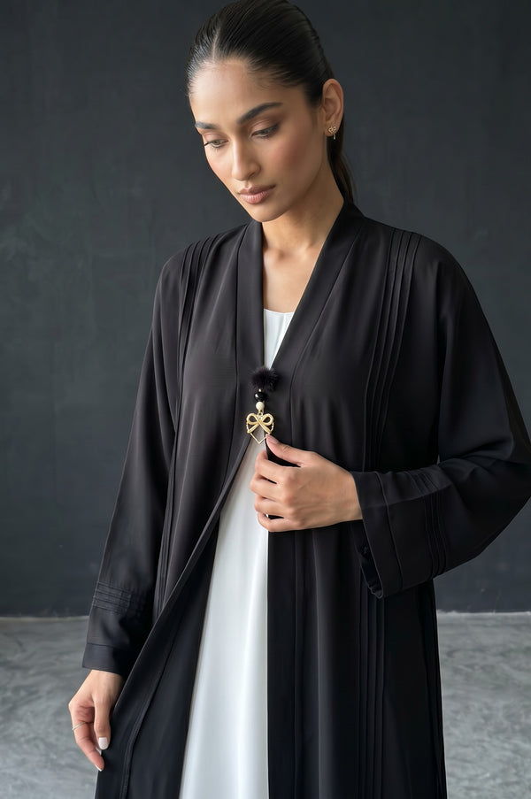 Styled front view of Monochrome Pleated Brooch Abaya showing vertical pintuck pleats