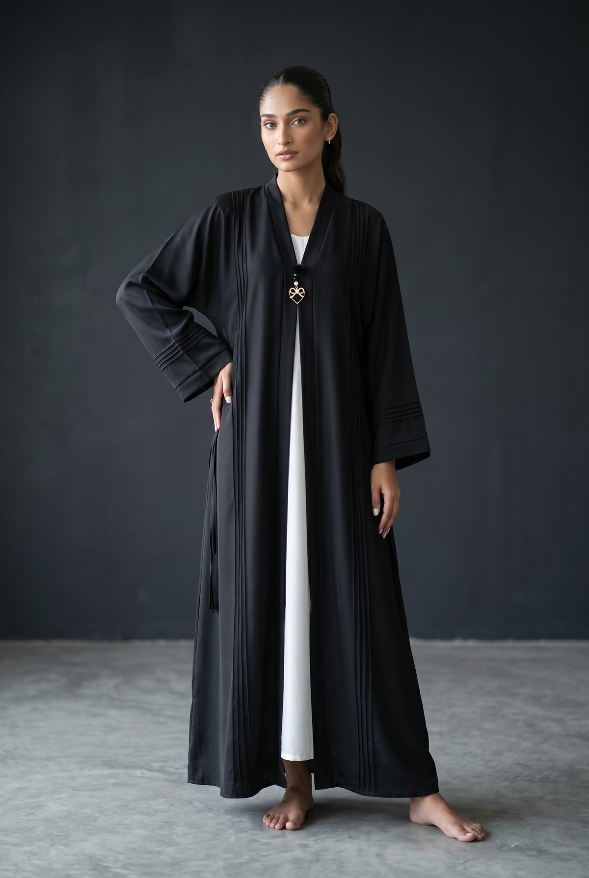 Full length standing view of Monochrome Pleated Brooch Abaya showing black and white color-block